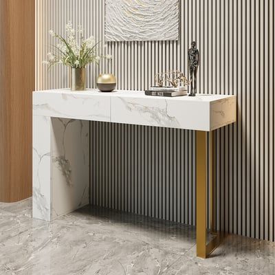 a white marble console table with gold legs in front of a striped wallpapered room