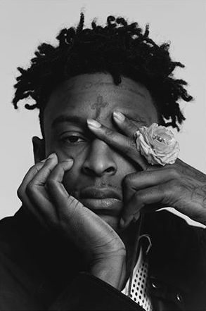 a black and white photo of a man with dreadlocks holding his hands to his face