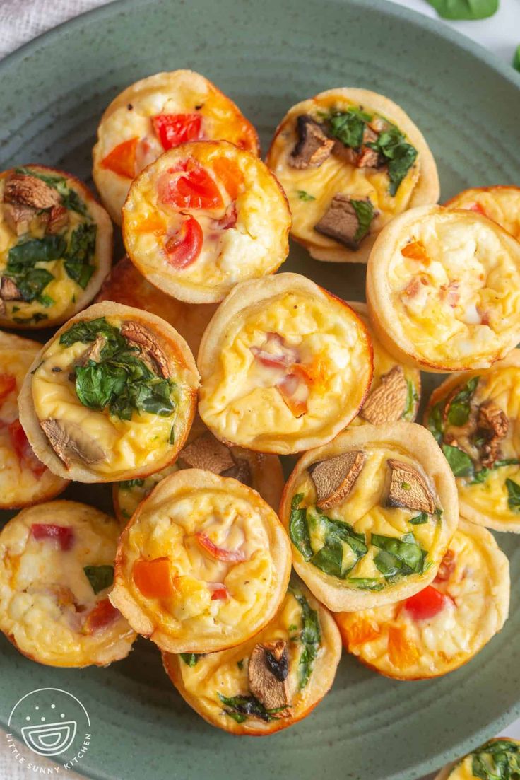 mini quiches filled with cheese and vegetables on a green plate next to other food items