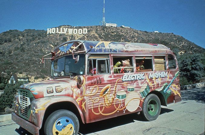 an old bus painted with graffiti parked in front of the hollywood sign