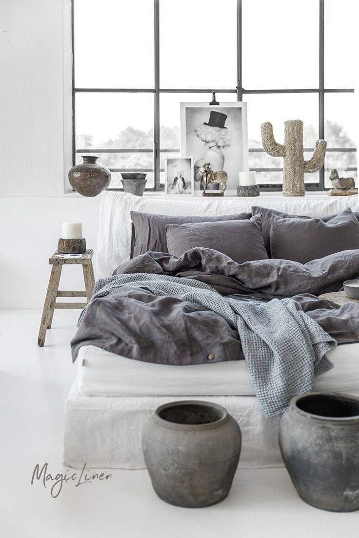 a bed with two vases on the side and a large window in the background