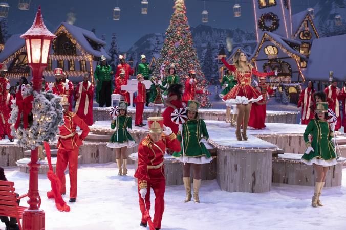 a group of people dressed in red and green outfits standing on top of snow covered ground