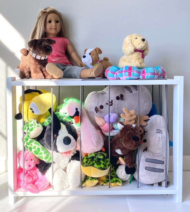 there are many stuffed animals in the toy rack on the shelf and one doll is wearing a pink shirt