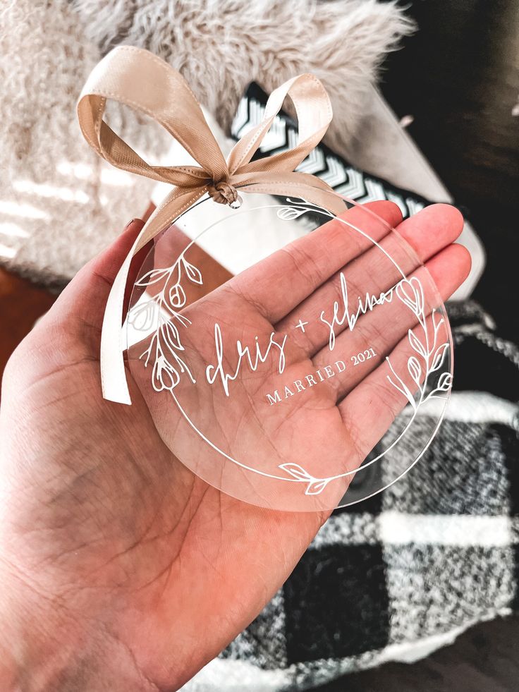 a person holding a clear ornament with a bow on it