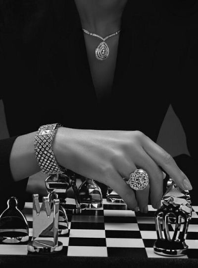 a black and white photo of a woman's hand on a chess board