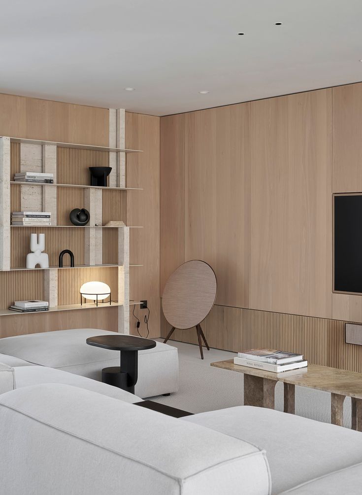 a living room filled with furniture and a flat screen tv mounted on a wall next to a wooden shelf