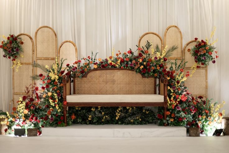 a bench decorated with flowers and greenery in front of a white curtained wall