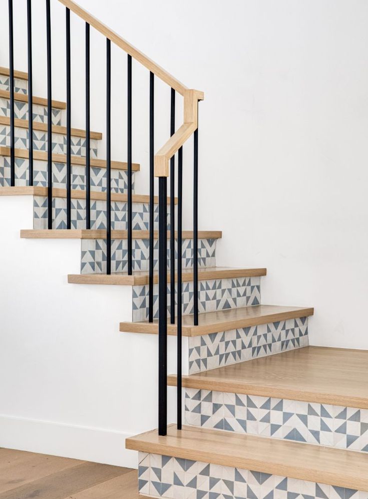 a stair case with blue and white tiles on the bottom, next to a wooden handrail