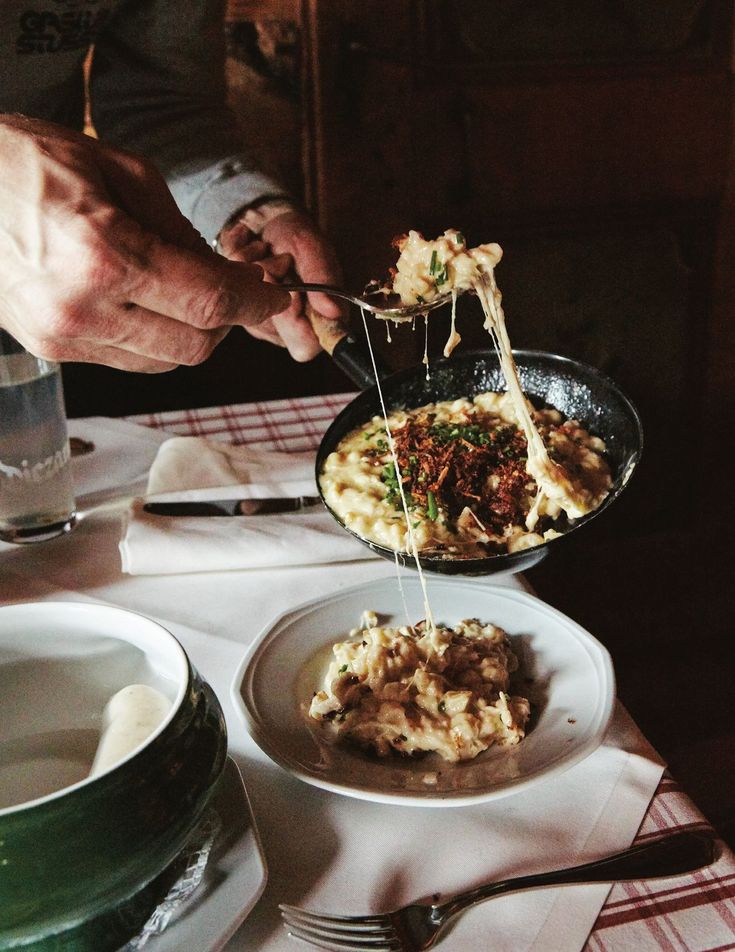 a person eating food from a pan on a table with other plates and utensils