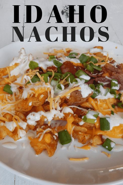 a white plate topped with nachos covered in cheese and toppings on top of it