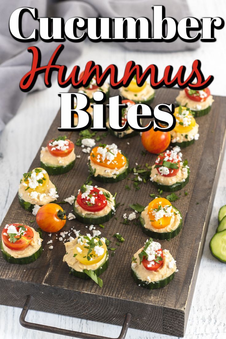 cucumber hummus bites on a cutting board with tomatoes, cheese and herbs