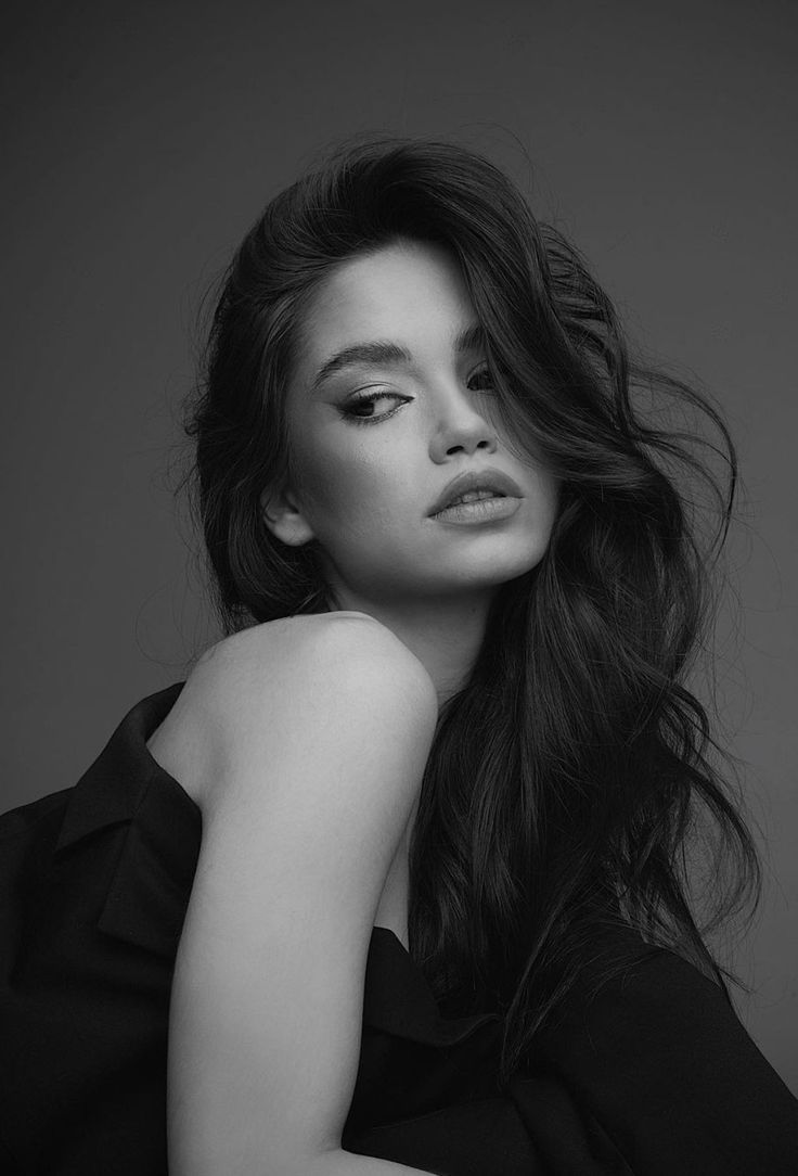 black and white photograph of a woman with long hair wearing a black dress posing for the camera