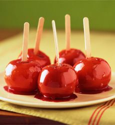 four candy apples on a plate with toothpicks in them