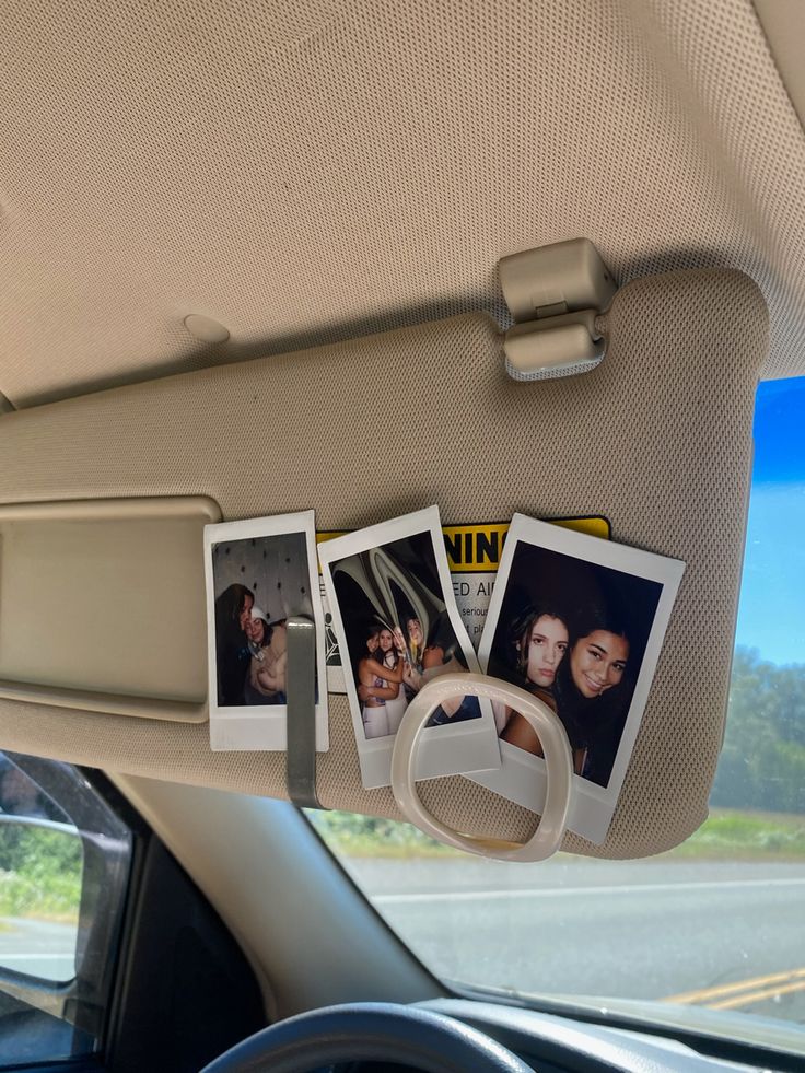 three polaroid photos hanging from the dash board of a car, in front of a windshield