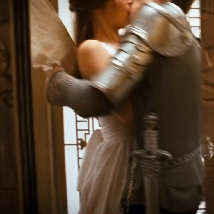 a man and woman dressed in armor kissing each other