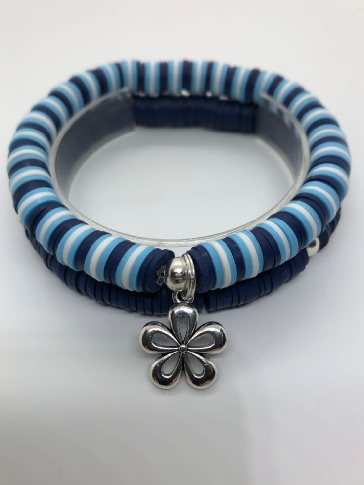 two blue and white striped bracelets with a silver flower charm on each one side