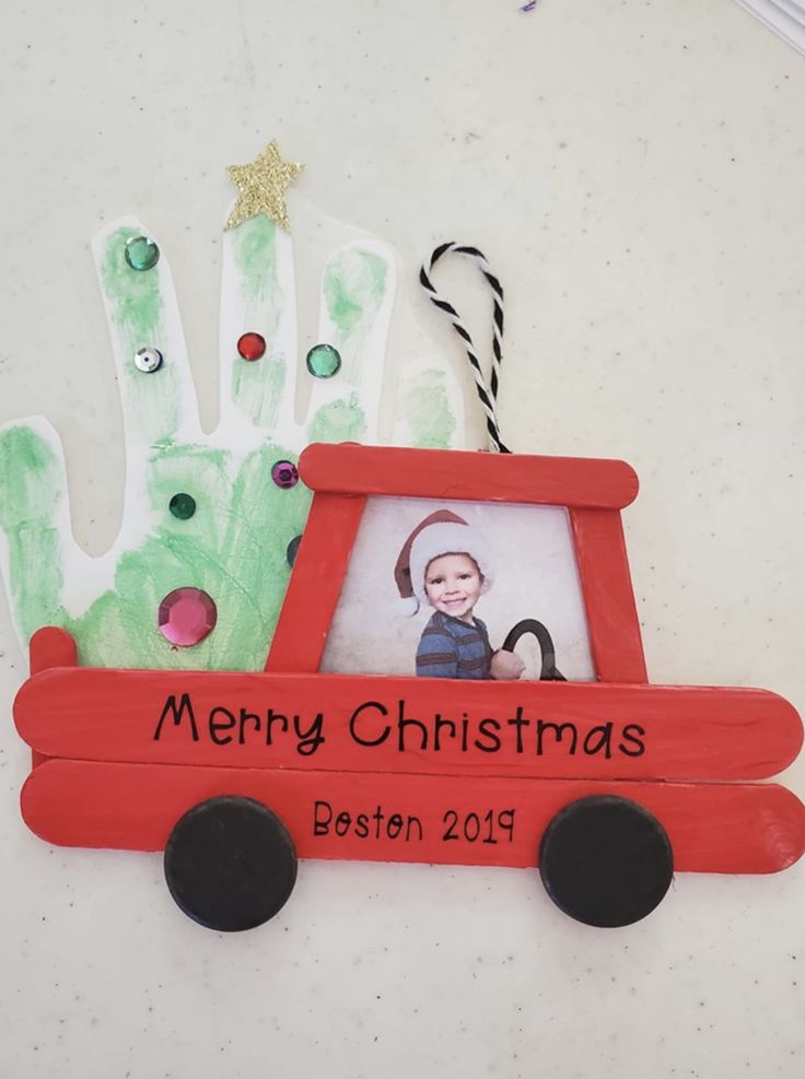 a christmas ornament with a handprint on it and a child's photo in the frame