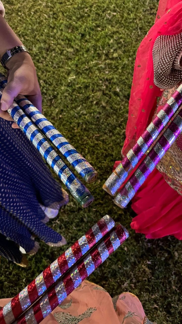 two people are holding colorful objects in their hands on the grass, one is wearing a red and blue dress