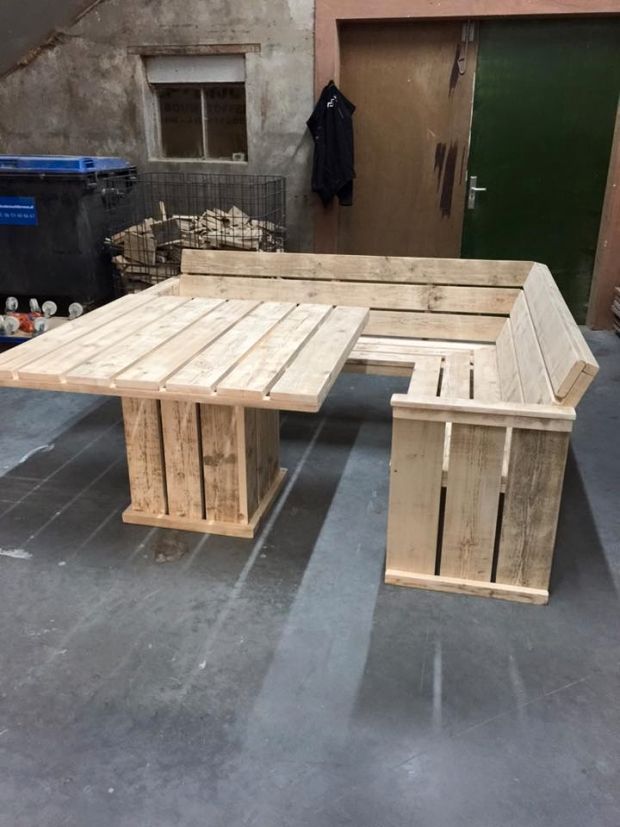 a table made out of wooden pallets sitting on top of a cement floor next to a building