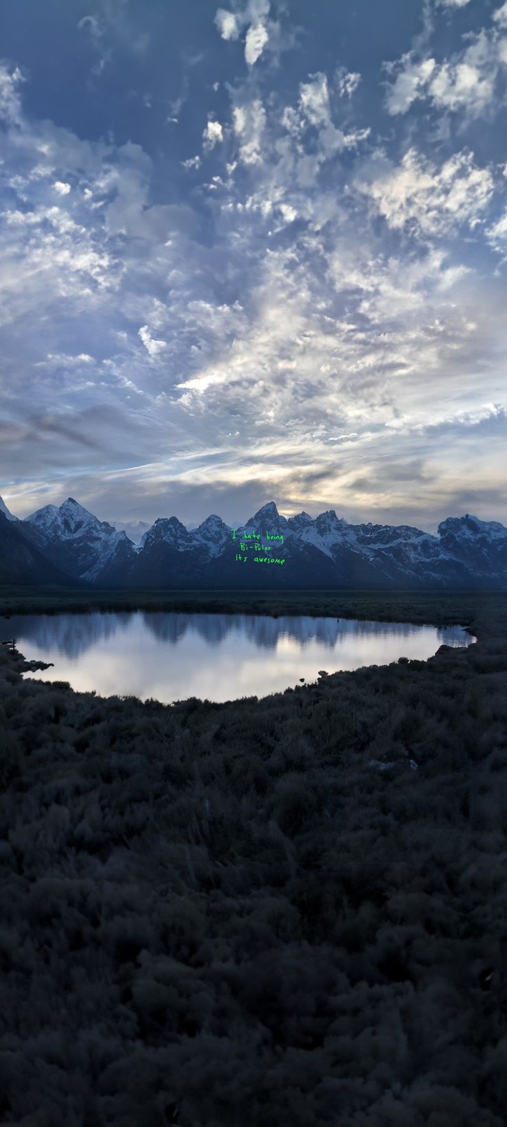 there is a lake in the middle of nowhere with mountains in the backgroud