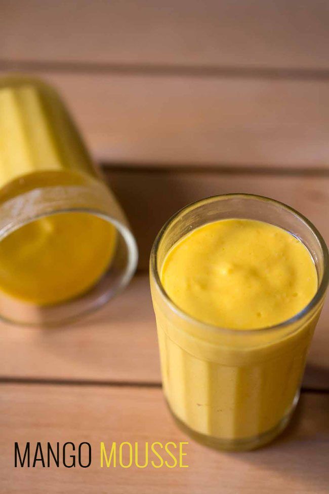 two glasses filled with yellow liquid sitting on top of a wooden table next to each other