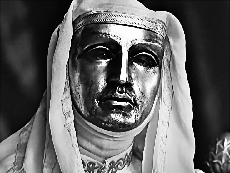 a black and white photo of a man wearing a headdress