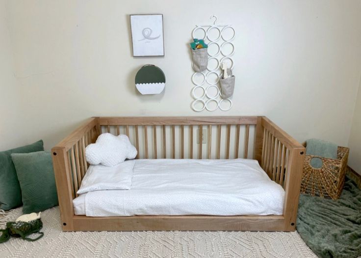 a baby crib in the corner of a room with pillows and blankets on the floor