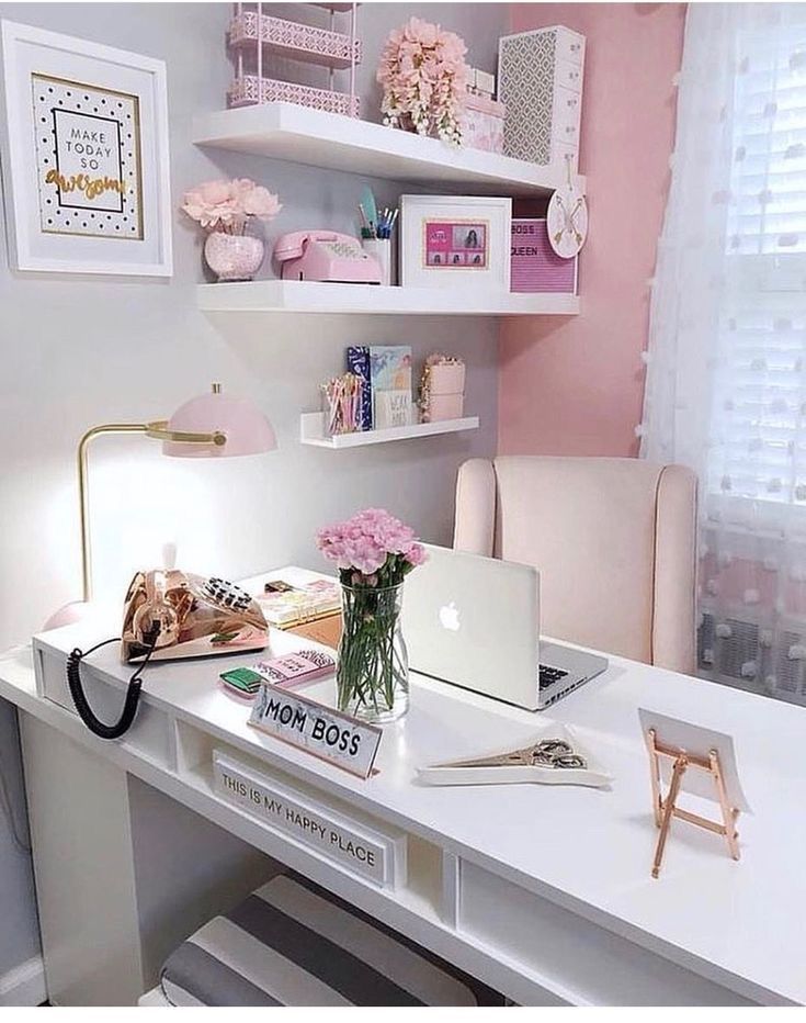 a white desk topped with a laptop computer next to a pink flower filled vase on top of it