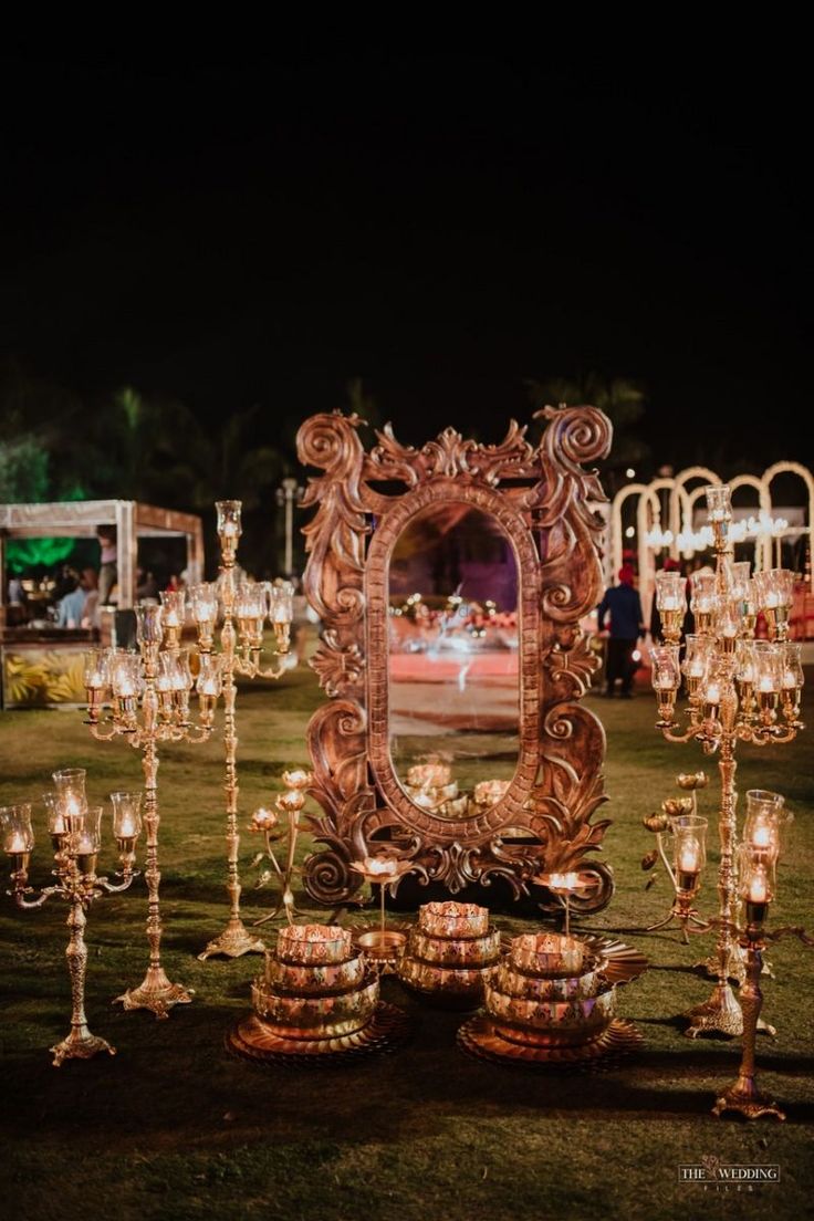 an ornate mirror surrounded by candles in the grass