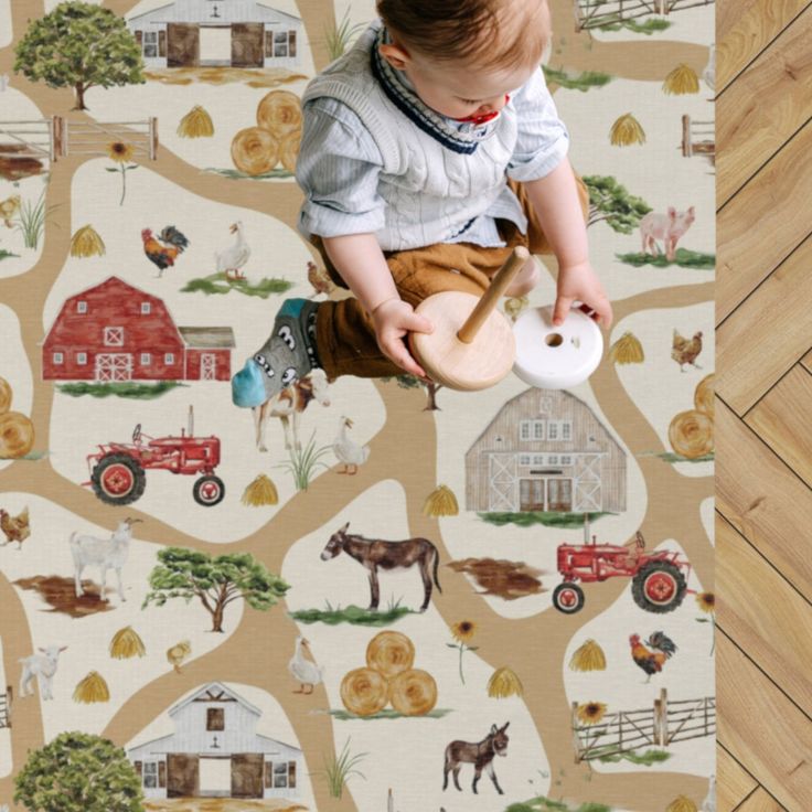 a baby is playing with a toy on the floor in front of a farm scene wallpaper