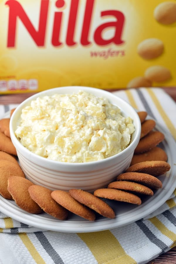 a white plate topped with crackers next to a bowl of whipped cream and a carton of nilla