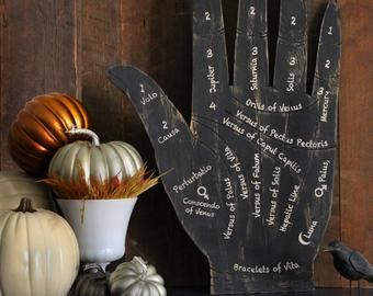 a wooden hand with writing on it next to pumpkins and other decorative items in front of a wood wall