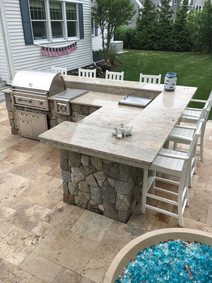 an outdoor kitchen and dining table with chairs