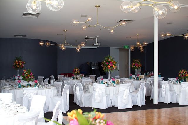 a banquet hall with tables and chairs covered in white linens, flowers and chandeliers