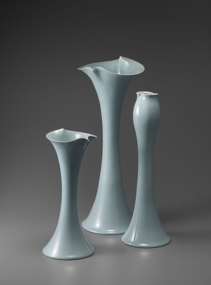 three blue vases sitting next to each other on a gray surface in front of a black background