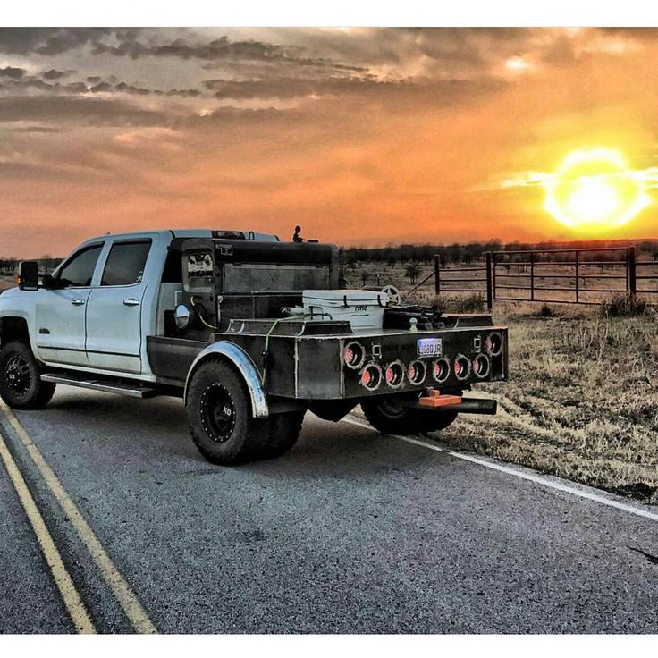 the truck is driving down the road in front of the setting sun on a cloudy day