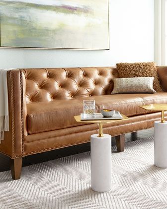 a brown leather couch sitting on top of a white rug