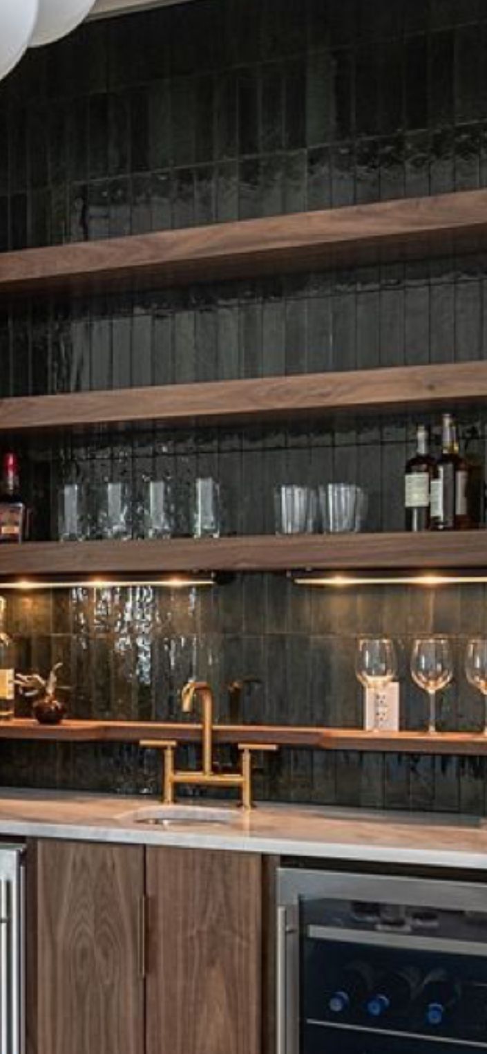 a kitchen with wine glasses and bottles on the shelves above the sink, next to an oven