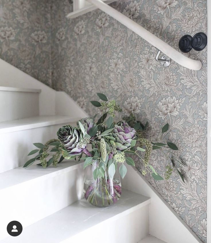 a vase filled with flowers sitting on the stairs