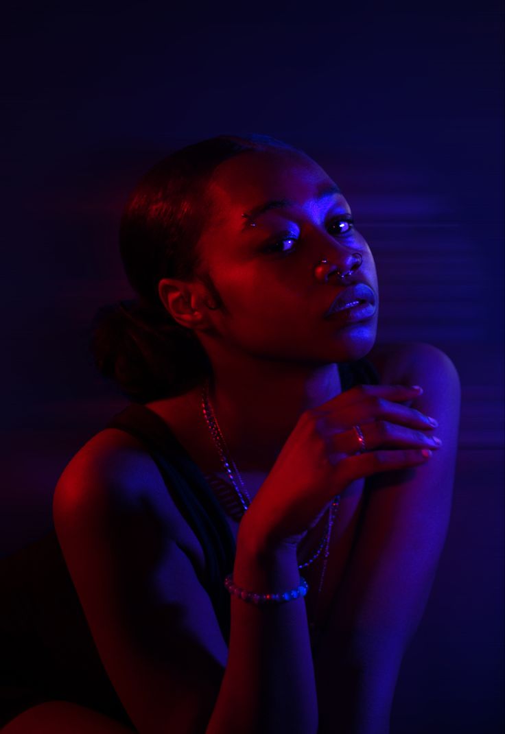 a woman sitting in the dark with her hands on her chest