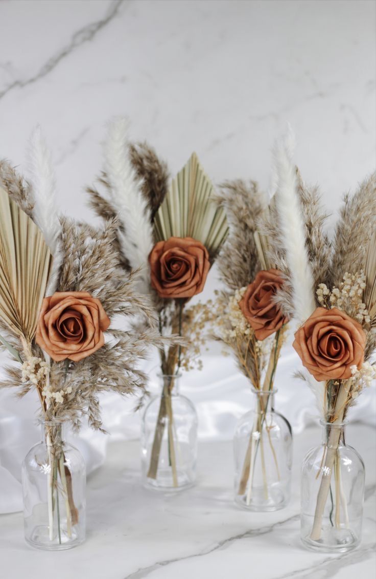 three vases with dried flowers and feathers in them