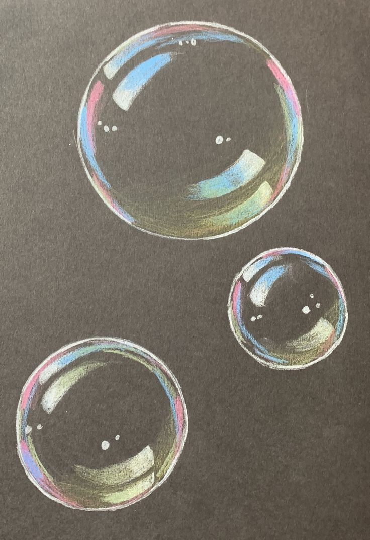 three soap bubbles sitting on top of a black tablecloth covered in pastel paint