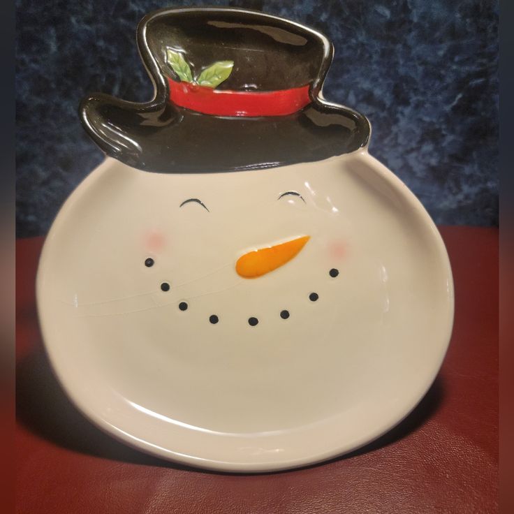 a white plate with a snowman face on it and a black hat on top