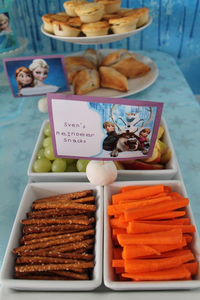 some food is sitting in trays on a blue tablecloth and there are other snacks