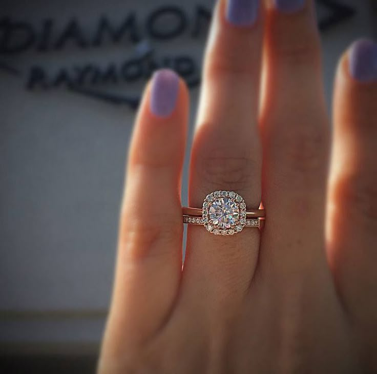 a woman's hand with a diamond ring on top of her finger and the other hand holding it