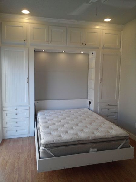 an empty bed frame in the middle of a room with white closets and drawers