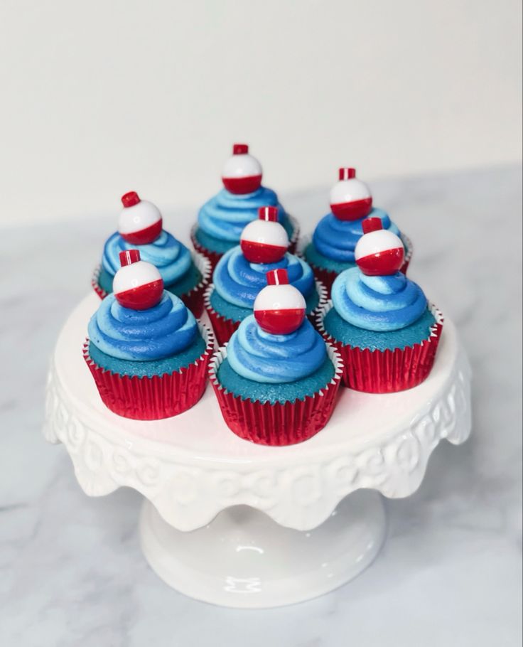 blue cupcakes with red and white decorations on a cake plate