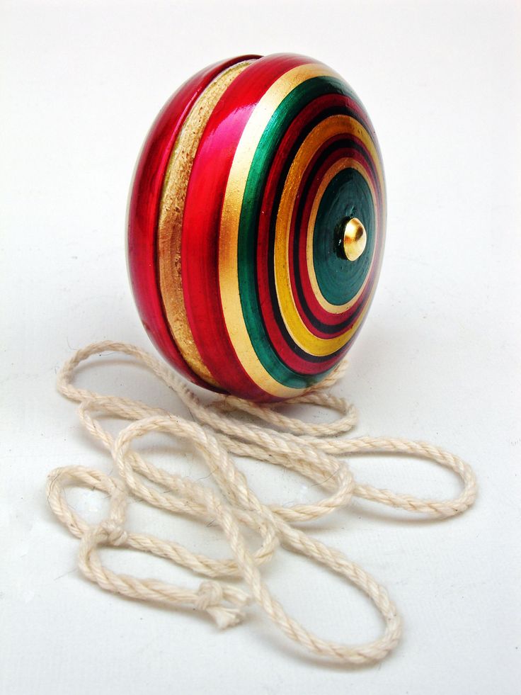 a red, yellow and green striped ball with string on white surface next to twine