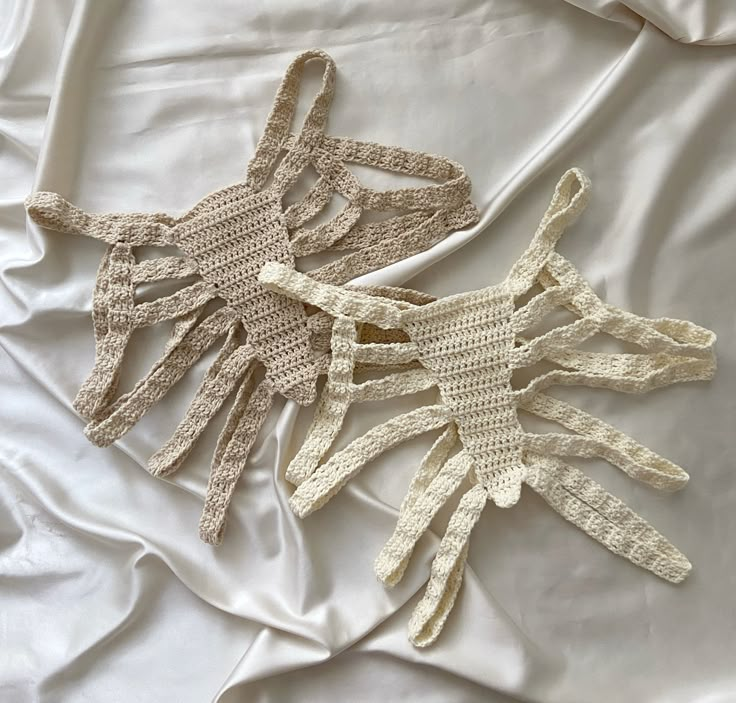 three crocheted gloves laying on top of a white bed sheet covered in sheets