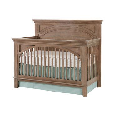 a wooden crib with a white bed in it